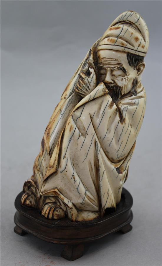 A Chinese mammoth ivory carving of a seated figure of Li Bai, holding a book, 16.5cm, wood stand